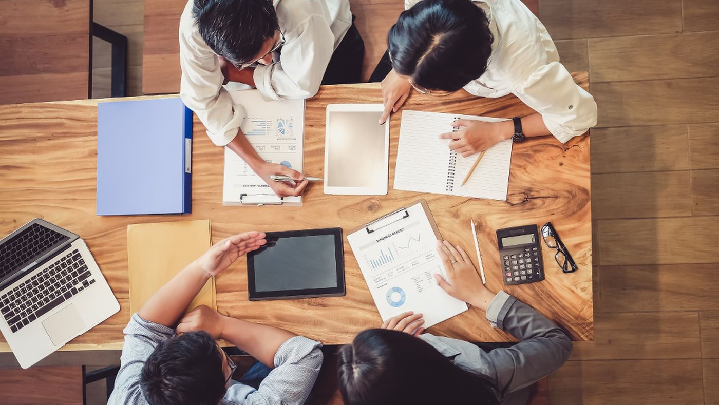 Advisers and clients reviewing financial reports and charts around a table