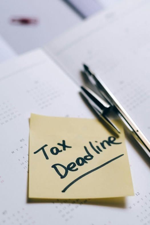 Handwritten tax deadline note beside a pen on a desk calendar